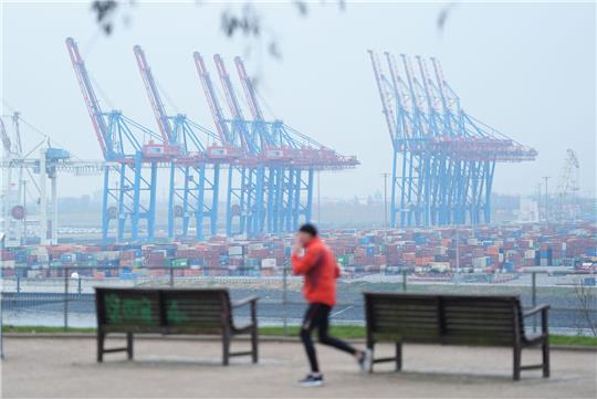 Ein Jogger läuft über den Altonaer Balkon. Im Hintergrund wind die Containerbrücken und des Container Terminals Tollerort im Hamburger Hafen zu sehen.