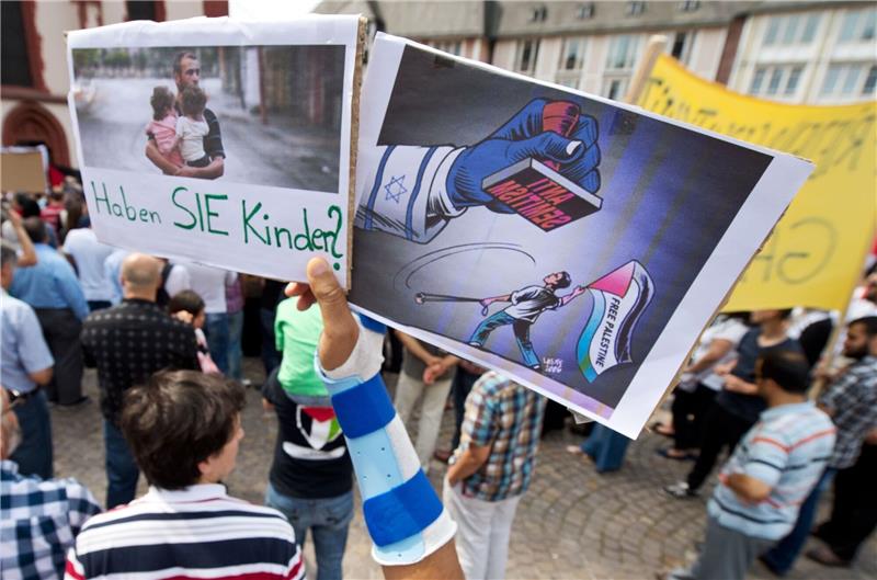 Islamforscherin: Beunruhigende Allianzen bei Antisemitismus Ein Junge hält ein Plakat hoch, auf dem ein propalästinensischer Demonstrant unter einem Stempel mit der Aufschrift "Anti Semitismus" steht.