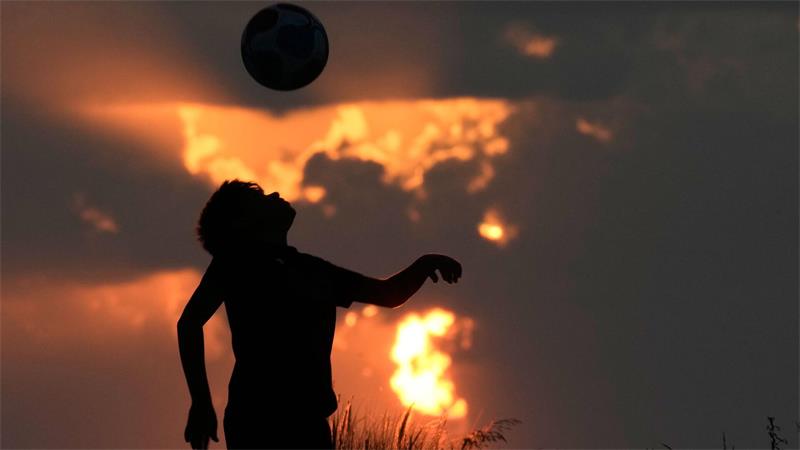 Ein Junge spielt Fußball, während die Sonne über der Mittelmeerküste in Beirut untergeht.