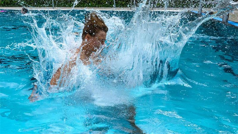 Ein Junge springt in das Becken eines Freibades in Leipzig. 
