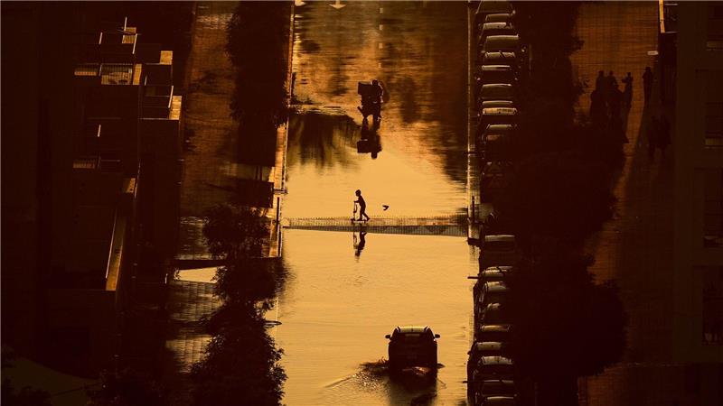 Ein Junge überquert eine mit Regenwasser gefüllte Straße in Schardscha, Vereinigte Arabische Emirate.