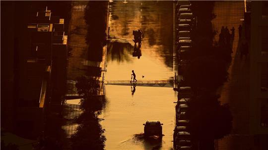 Ein Junge überquert eine mit Regenwasser gefüllte Straße in Schardscha, Vereinigte Arabische Emirate.