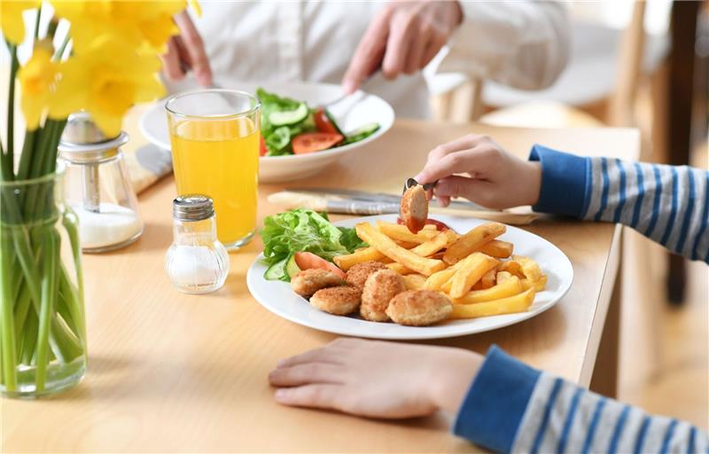 Ein Junge vor einem Teller mit Chicken Nuggets und Pommes Frites (Symbolbild).