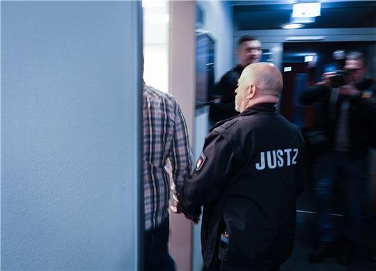 Ein Justizbeamter begleitet den Angeklagten in den Gerichtssaal.
