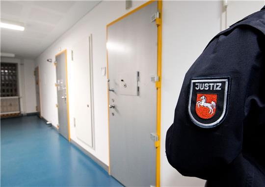 Ein Justizbeamter steht neben Zellen von Gefangenen.