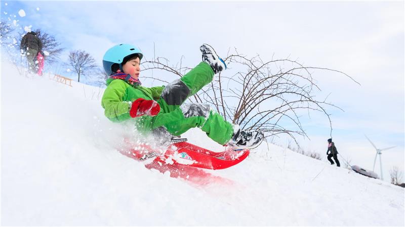 Mit Zugdrachen und Brett – Snowkiten in Hannover Ein Kind fährt mit seinem Schlitten am Kronsberg.