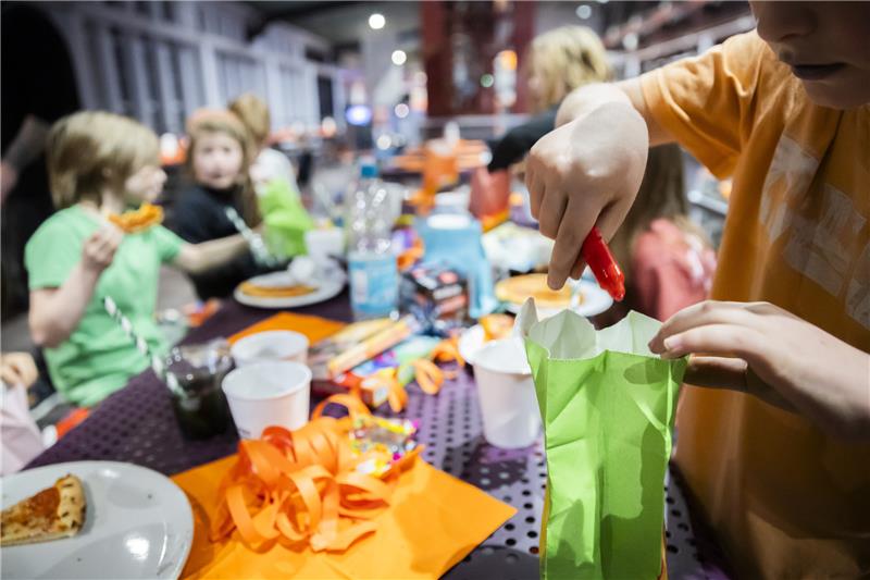 Ein Kind öffnet bei einem Kindergeburtstag im Jump House Berlin-Reinickendorf eine Geschenktüte.  Foto: Christoph Soeder/dpa
