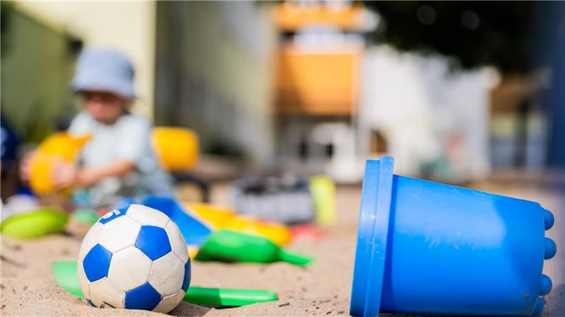 Ein Kind spielt in einem Sandkasten - wo haben dessen Eltern wohl Eimerchen, Schaufeln und den kleinen Ball gekauft, im Internet oder im Geschäft?