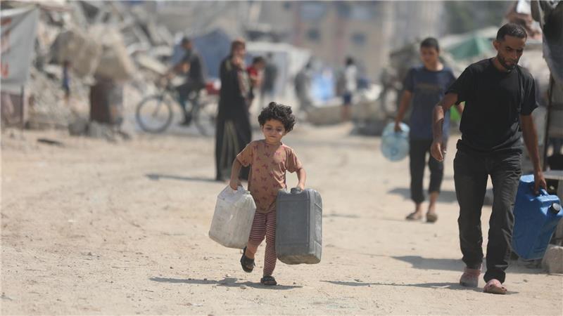 Bilder des Tages Ein Kind trägt Kanister, um sich in Gaza Wasser von einem Tankwagen zu holen.