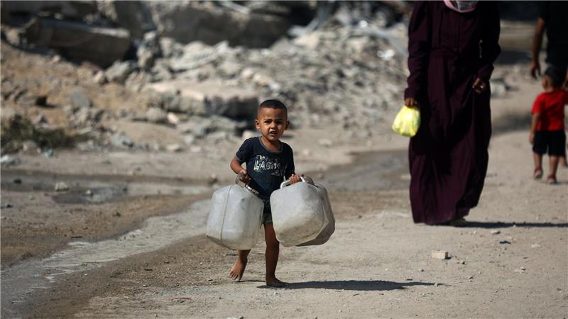 Ein Kind trägt Kanister, während Palästinenser versuchen, ihren täglichen Wasserbedarf zu decken, indem sie Kanister aus Wassertankwagen füllen, die in das Gebiet in Gaza-Stadt gebracht wurden.