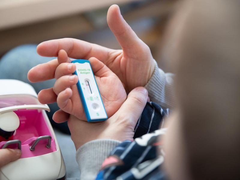 Ein Kita-Kind und seine Mutter warten daheim auf das Ergebnis eines Corona-Selbsttests. Foto: Friso Gentsch/dpa