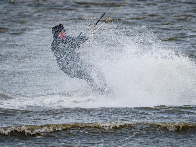 Ein Kitesurfer zieht im Meer seine Bahnen. Foto: Axel Heimken/dpa/Symbolbild