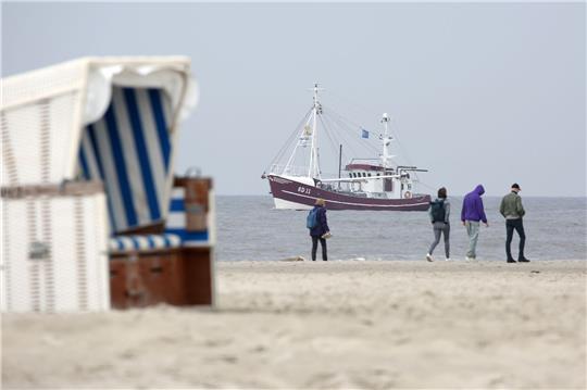 Ein Krabbenkutter fährt auf der Nordsee am Strand von St. Peter-Ording entlang.