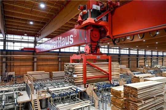 Ein Kran hebt eine Ladung Holz an, um diese in einer Halle der SchwörerHaus KG zu einem anderen Platz zu transportieren.
