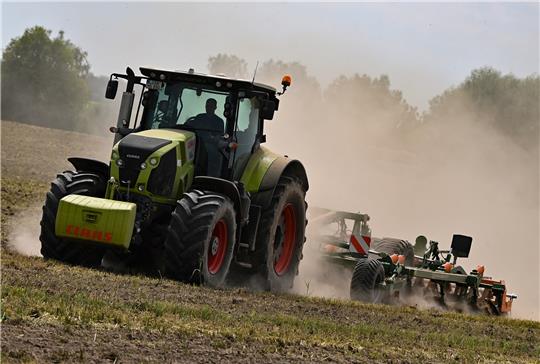 Ein Landwirt bearbeitet den trockenen Boden auf einem Feld und wirbelt dabei viel Staub auf. Brandenburg ist von Jahr zu Jahr mehr von Trockenheit betroffen. Das Land um Berlin leidet zudem unter den sandigen Böden, die den Regen nicht lange halten können. Foto: picture alliance/dpa | Patrick Pleul