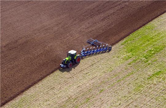 Ein Landwirt pflügt ein abgeerntetes Feld und bereitet es für die Neubestellung vor.