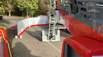 Eine rote Leiter der Feuerwehr ist über einen mit einer Schutzwand abgeschirmten Platz ausgefahren.
