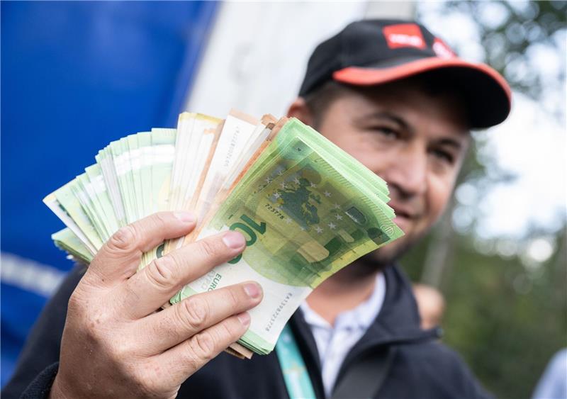 Streikende Fahrer hoffen auf Geld und Dominoeffekt Ein Lkw-Fahrer mit einem Bündel Geldscheinen in der Hand.