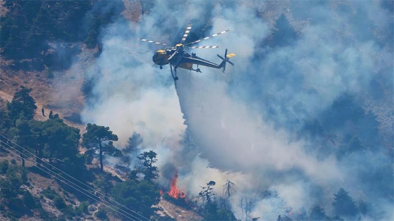 Ein Löschhubschrauber wirft Wasser über einem Waldbrand nordwestlich von Athen ab.