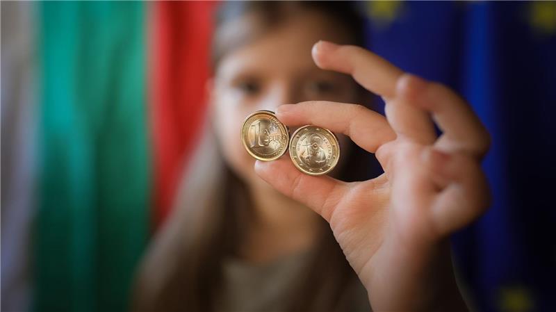 Ein Mädchen zeigt neue Euro-Münzen mit bulgarischen Symbolen.