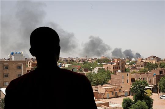 Ein Mann blickt auf die Stadt Khartum, wo schwarzer Rauch aufsteigt. Seit nun mehr vier Monaten bekämpfen sich die Konfliktparteien im Sudan.