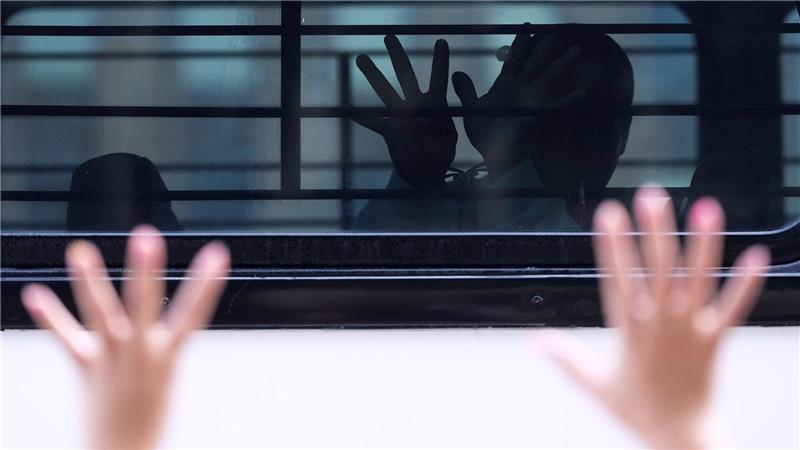 Bilder des Tages Ein Mann, der nach einem Auftritt vor dem Einwanderungsgericht in San Antonio von Bundesbeamten festgenommen und in einen Bus gesetzt wurde, versucht durch vergitterte und getönte Fenster zu kommunizieren.