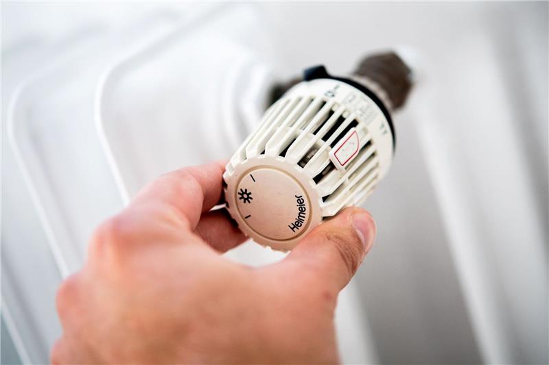 Wasserstoff für Endkunden langfristig nicht teurer als Gas Ein Mann dreht in einer Wohnung am Thermostat einer Heizung.