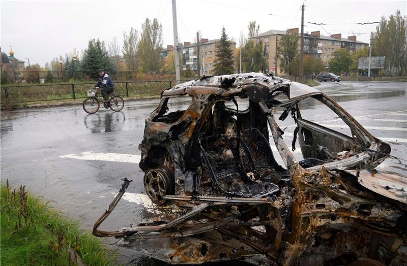 Krieg gegen die Ukraine: So ist die Lage Ein Mann fährt in Bachmut mit seinem Fahrrad an einem Auto vorbei, das durch Beschuss zerstört wurde.