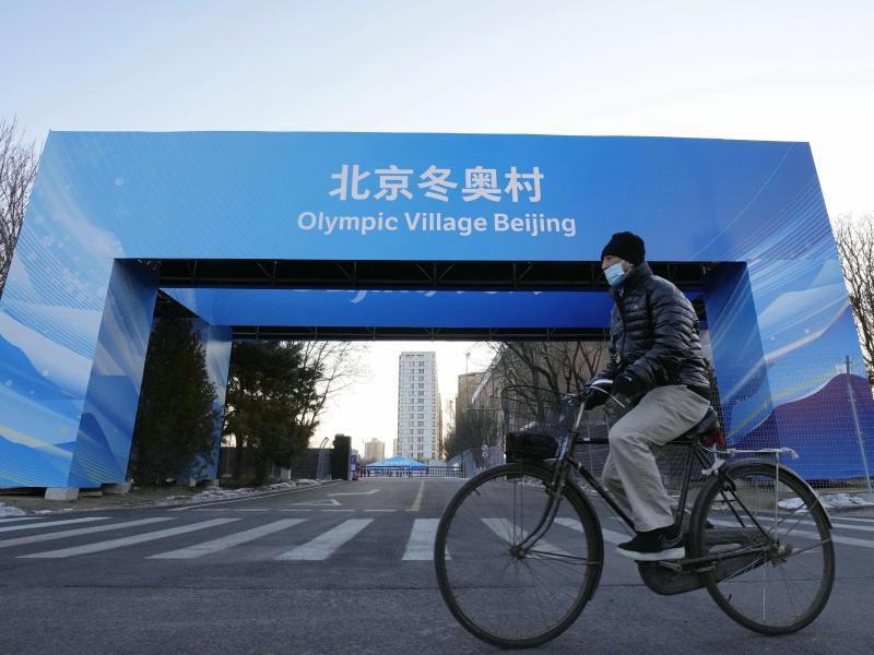 Ein Mann fährt in der Nähe des Athletendorfs in der chinesischen Hauptstadt Peking Fahrrad. Foto: -/Kyodo/dpa