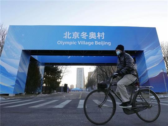 Ein Mann fährt in der Nähe des Athletendorfs in der chinesischen Hauptstadt Peking Fahrrad. Foto: -/Kyodo/dpa