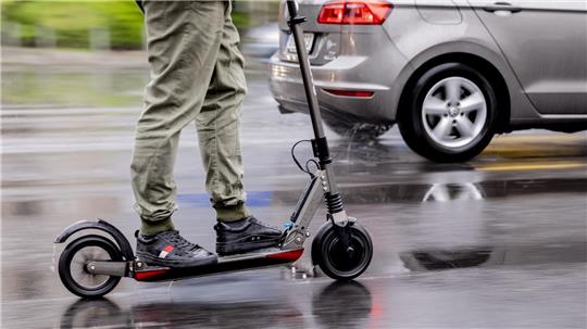 Ein Mann fährt mit einem E-Scooter auf der Straße. 
