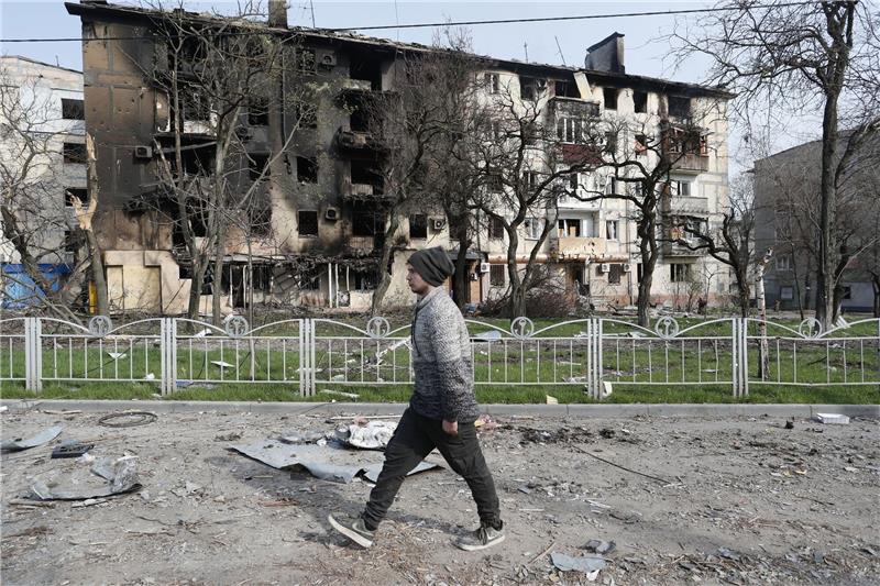 Ein Mann geht in der Nähe eines durch Beschuss zerstörten Wohnhauses in Mariupol.