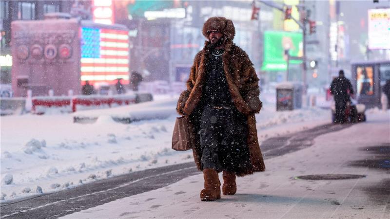Ein Mann geht während eines Schneesturms über den Times Square in New York.