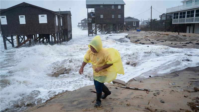 Ein Mann geht während eines Sturmes an einsturzgefährdeten Häusern vorbei.