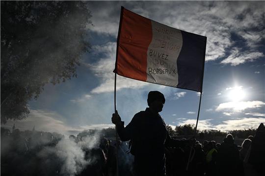 Ein Mann hält eine französische Nationalflagge mit der Aufschrift «Winzer in Gefahr - trinkt Bordeaux-Wein» hoch.