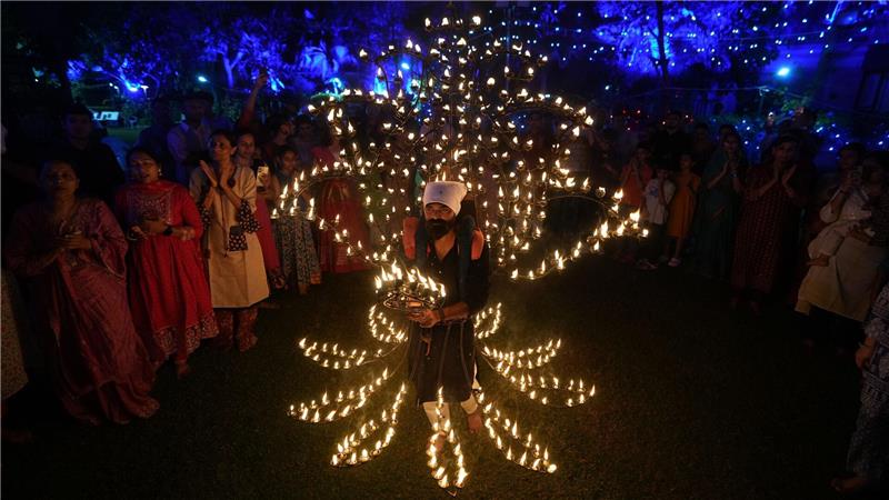 Ein Mann hält in einem mit Öllampen geschmückten Kostüm in der fünften Nacht von Navratri, dem Fest der neun Nächte, das Aarti-Ritual ab.