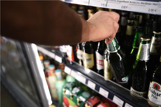 Ein Mann holt eine Flasche Bier aus einem Kühlschrank in einem Kiosk. Foto: Sven Braun/DPA