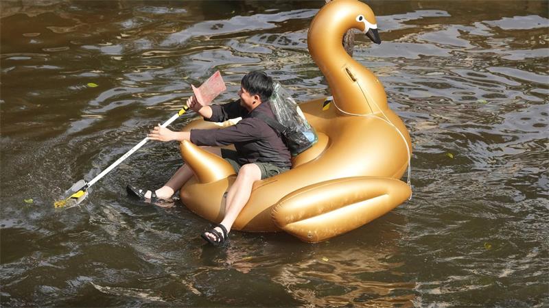 Ein Mann paddelt nach tagelangen starken Regenfällen auf einem Schwimmtier in Form eines goldenen Schwans durch eine überflutete Straße in der thailändischen Hauptstadt.