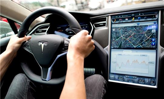 Ein Mann sitzt in einem Tesla Model S am Lenkrad: Elon Musk sagt, er sei mit seinen Versprechen zu selbstfahrenden Autos oft zu optimistisch gewesen.