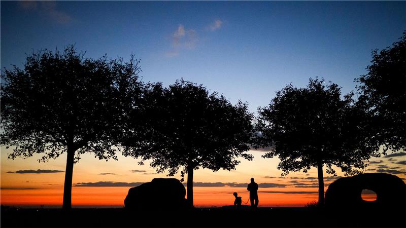 Bilder des Tages Ein Mann spaziert am frühen Morgen kurz vor Sonnenaufgang mit einem Hund über den Kronsberg.