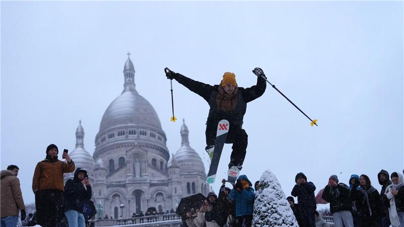 Ein Mann springt mit seinen Skiern den Hügel bei der Basilika Sacre-Coeur im französischen Paris hinunter.