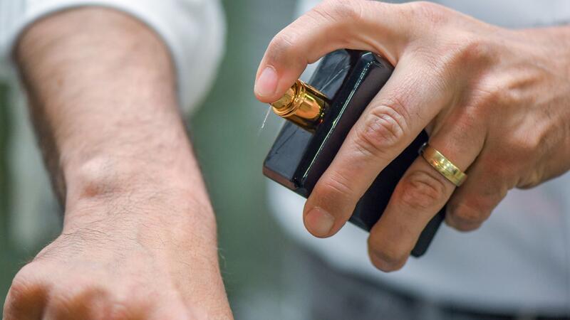 Wenn der Gast einem stinkt: Tut ein Duft-Dresscode not? Ein Mann sprüht sich Parfum auf die Hand - Experten geben den Tipp: An Stellen, die gut durchblutet sind (zum Beispiel hinter den Ohren, am Puls oder der Armbeuge), wirken Düfte besonders intensiv. (Archivbild)