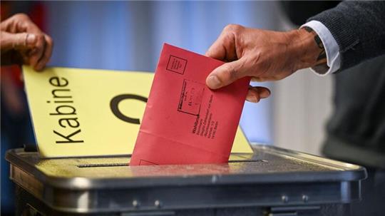 Ein Mann steckt seine Stimmzettel in einem Briefumschlag in die Wahlurne.