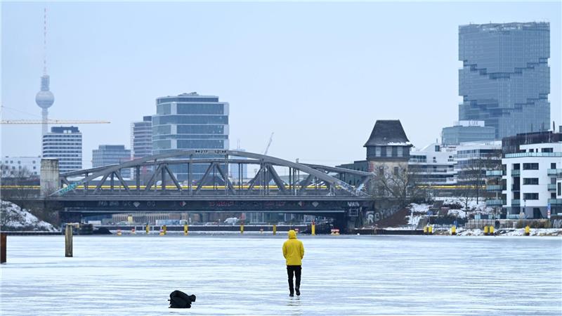 Ein Mann steht am Treptower Park in Berlin auf der zugefrorenen Spree.
