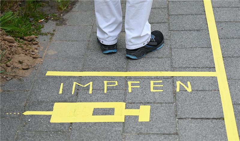 Corona-Impfquoten: Bremen schlechter, Niedersachsen besser Ein Mann steht an einem Covid-19-Impfcenter hinter der Bodenaufschrift «Impfen».