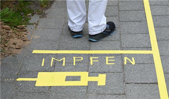 Ein Mann steht an einem Covid-19-Impfcenter hinter der Bodenaufschrift «Impfen».