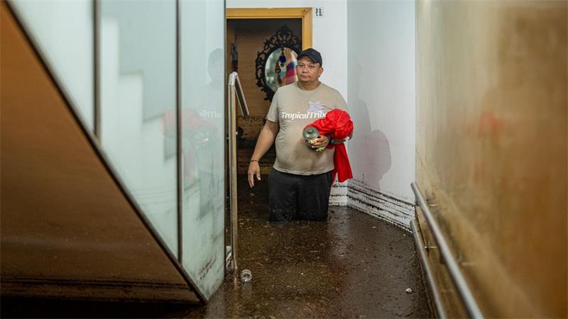 Ein Mann steht im Treppenhaus eines Gebäudes in der an Barcelona grenzenden Stadt L’Hospitalet de Llobregat in mehr als knietiefem Wasser. 