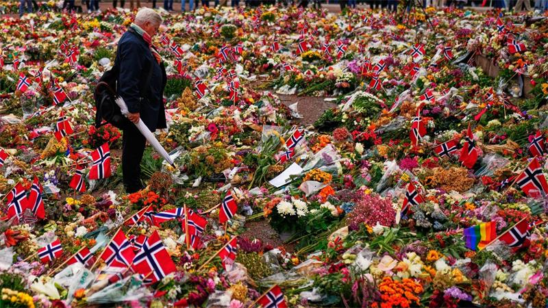 Ein Mann steht in Oslo zwischen den Blumengestecken für den verstorbenen norwegischen König Harald.