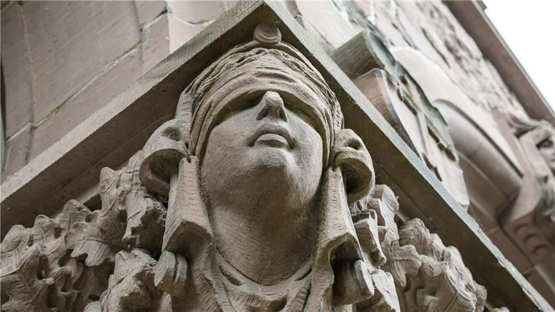 Ein Mann stirbt unerwartet im Amtsgericht Oldenburg. Eine Skulptur der Justitia hängt an einer Säule an dessen Eingang. (Symbolbild)