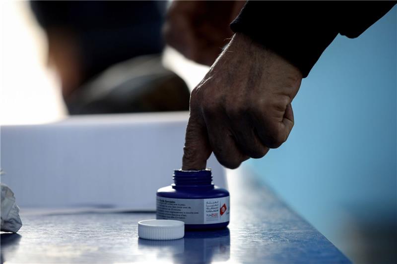 Ein Mann taucht seinen Finger in Tinte bei seiner Stimmabgabe in einem Wahllokal für die tunesischen Parlamentswahlen 2022.
